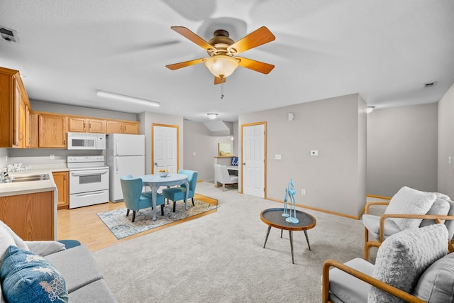 living area featuring a ceiling fan, light wood-style floors, and baseboards