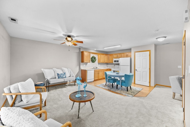 living area featuring light carpet, ceiling fan, visible vents, and baseboards