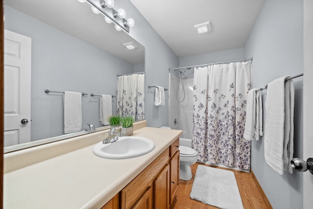 full bath with toilet, shower / tub combo with curtain, wood finished floors, and vanity