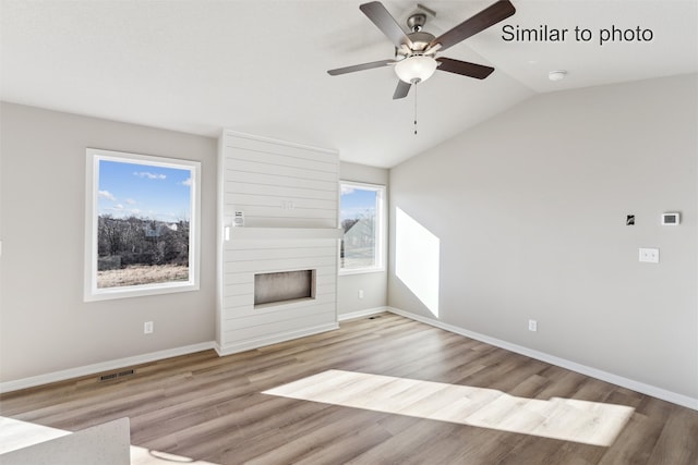 unfurnished living room with ceiling fan, a large fireplace, light wood-type flooring, and lofted ceiling