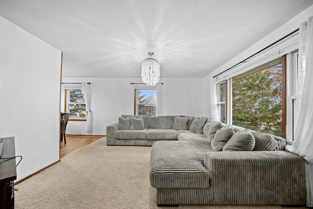 living room featuring light colored carpet, a textured ceiling, and an inviting chandelier