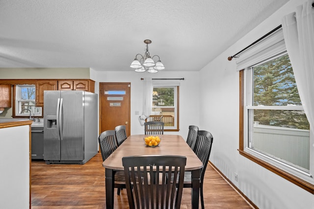 dining space featuring a notable chandelier, light hardwood / wood-style floors, and a textured ceiling