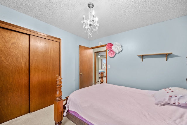 bedroom featuring a closet, carpet, a textured ceiling, and an inviting chandelier