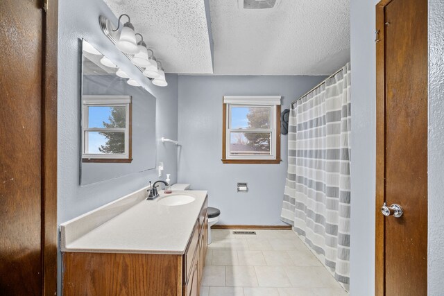 bathroom with a textured ceiling, vanity, and plenty of natural light