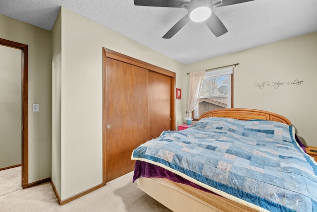 bedroom with a textured ceiling, ceiling fan, light carpet, and a closet