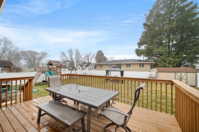 wooden terrace with a playground, a lawn, a gazebo, and a shed