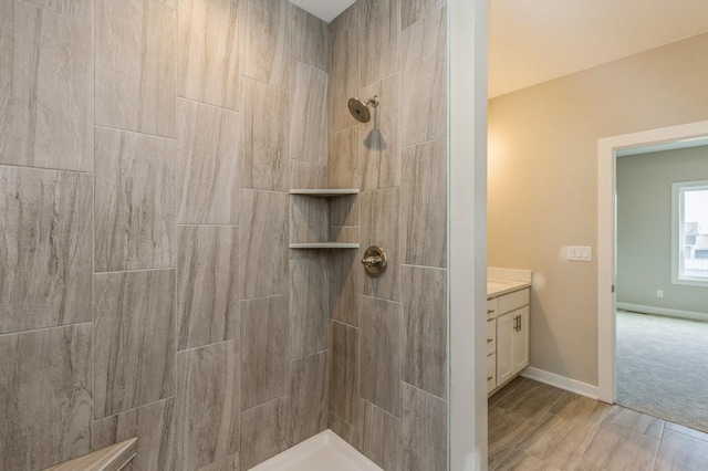 bathroom with a tile shower and vanity