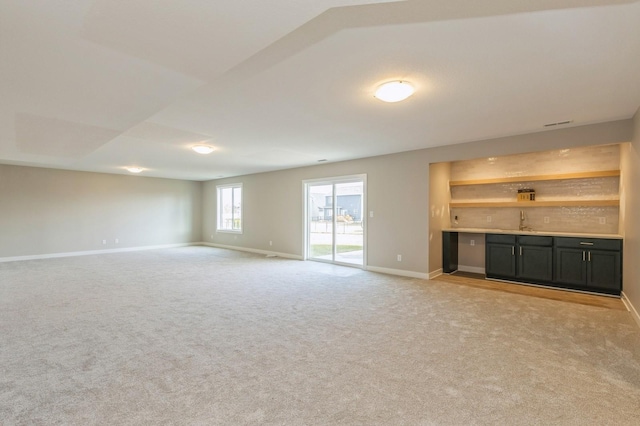 unfurnished living room with light colored carpet and indoor bar