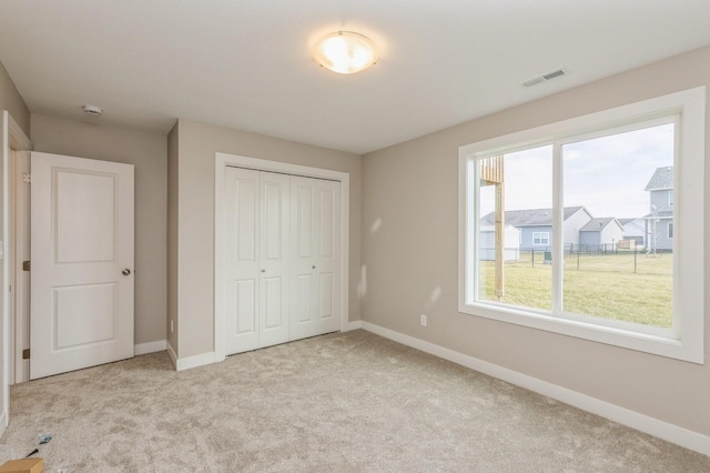 unfurnished bedroom with a closet and light colored carpet