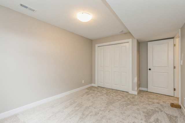 unfurnished bedroom with light carpet and a closet