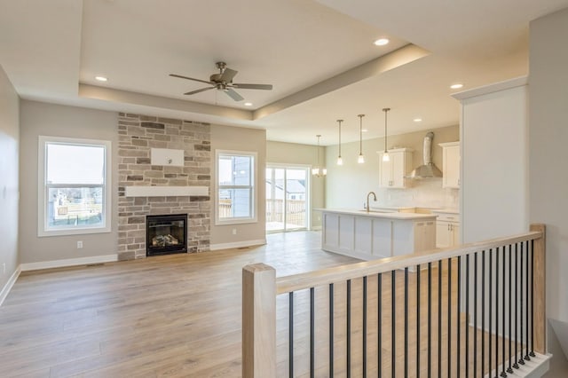 unfurnished living room featuring a raised ceiling, a fireplace, and light hardwood / wood-style flooring