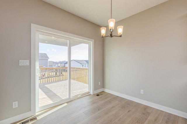 unfurnished room with a chandelier and light wood-type flooring