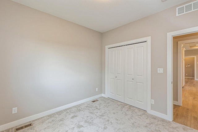 unfurnished bedroom with light carpet and a closet