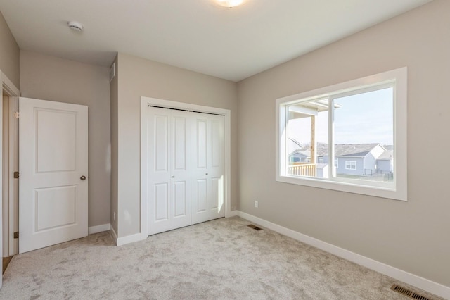 unfurnished bedroom featuring a closet and light colored carpet