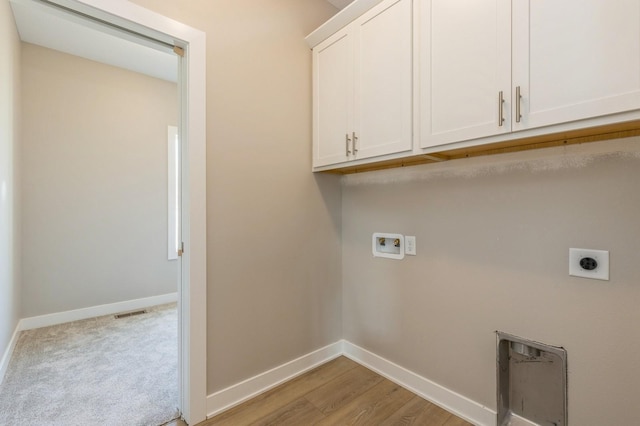 laundry room with electric dryer hookup, hookup for a washing machine, cabinets, and light wood-type flooring