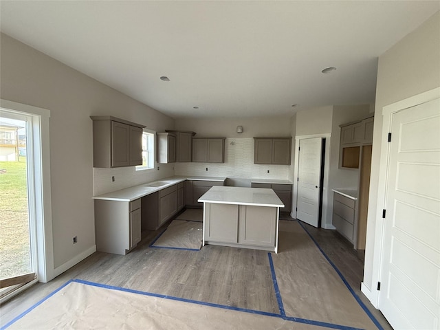 kitchen featuring gray cabinets, a center island, backsplash, and a wealth of natural light