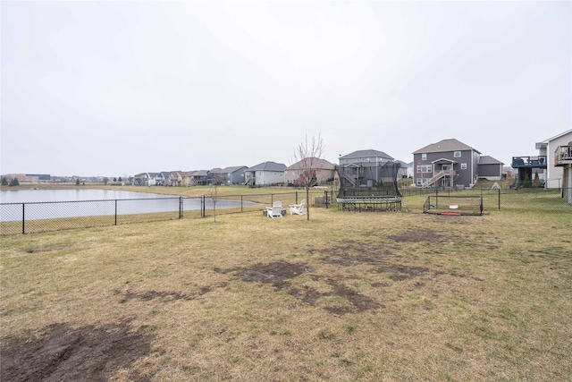 view of yard with fence, a playground, a trampoline, and a water view