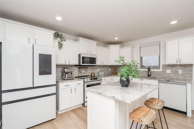 kitchen featuring a sink, light wood-type flooring, white appliances, and white cabinetry