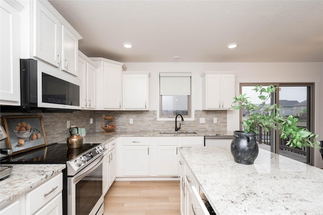 kitchen with electric range, a sink, white cabinets, decorative backsplash, and white microwave