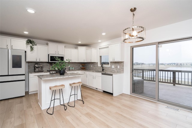 kitchen featuring light wood-style flooring, a center island, fridge, white cabinets, and white dishwasher