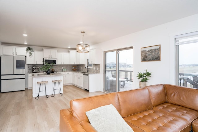 kitchen featuring open floor plan, a breakfast bar, decorative backsplash, appliances with stainless steel finishes, and a sink