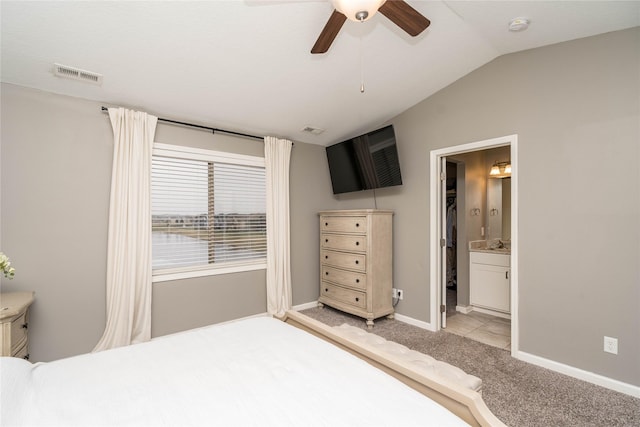 bedroom featuring visible vents, ensuite bathroom, baseboards, light colored carpet, and vaulted ceiling