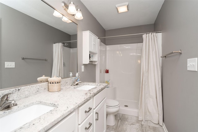 bathroom featuring double vanity, a stall shower, toilet, and a sink