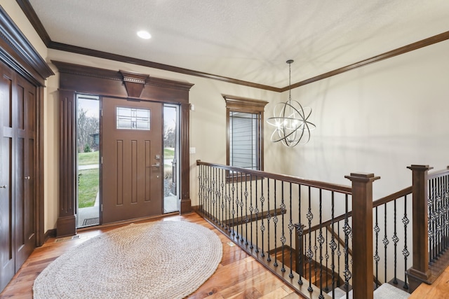 entrance foyer featuring ornamental molding, light wood-type flooring, and a notable chandelier