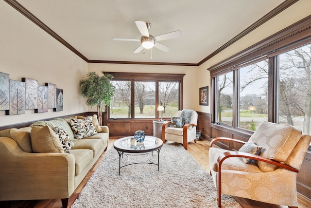 living room with ornamental molding, light wood-type flooring, ceiling fan, and a healthy amount of sunlight