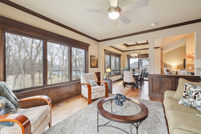 living room with crown molding, light hardwood / wood-style floors, and ceiling fan with notable chandelier