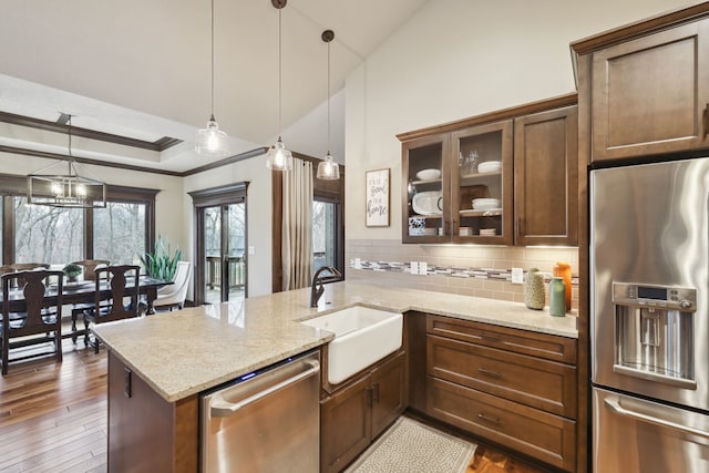 kitchen featuring decorative backsplash, appliances with stainless steel finishes, light stone countertops, sink, and decorative light fixtures