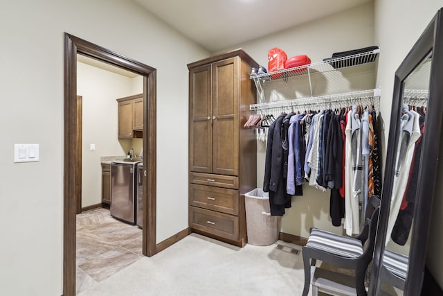 walk in closet featuring washer and clothes dryer and light colored carpet