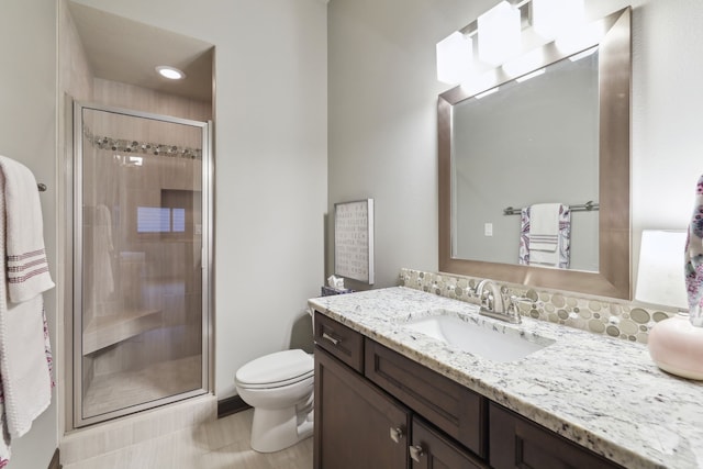 bathroom featuring tile patterned flooring, vanity, toilet, and a shower with shower door