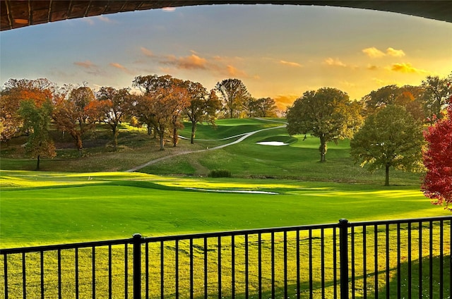 view of property's community with view of golf course, fence, and a yard