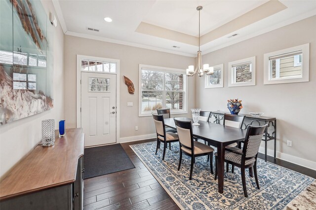 dining room featuring a notable chandelier, a raised ceiling, ornamental molding, and dark wood-type flooring