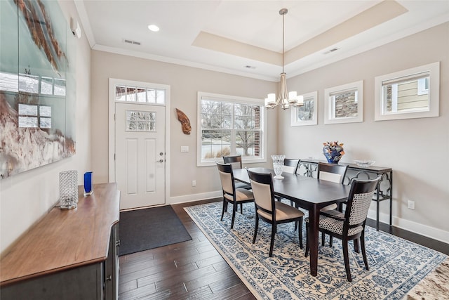 dining space with baseboards, visible vents, a raised ceiling, dark wood-style floors, and crown molding