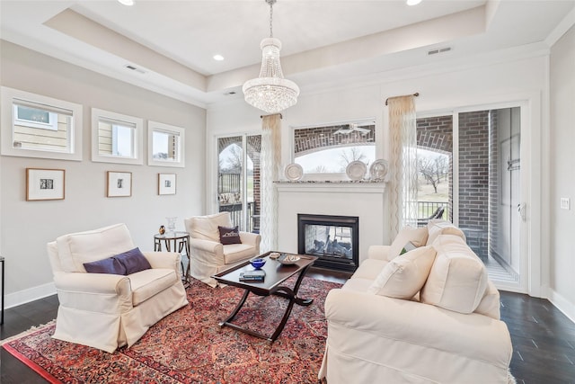 living area with dark wood-type flooring, a raised ceiling, and baseboards