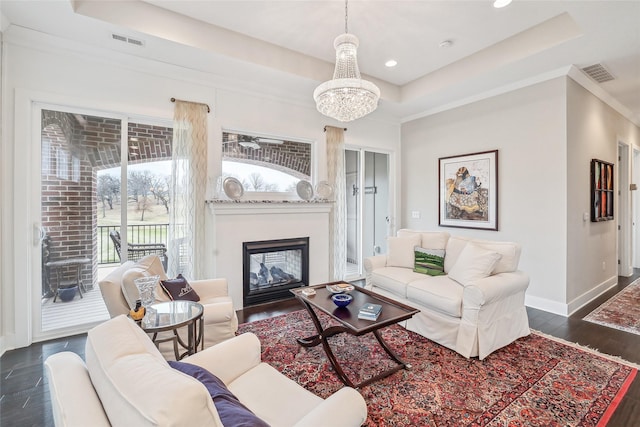 living area featuring a tray ceiling, visible vents, and baseboards