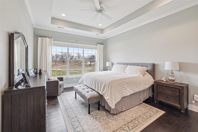 bedroom with crown molding, baseboards, a raised ceiling, and dark wood-type flooring