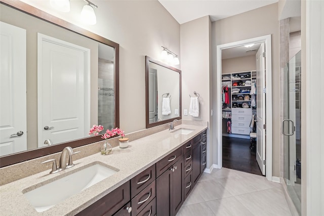 full bath with double vanity, a stall shower, a sink, and a walk in closet