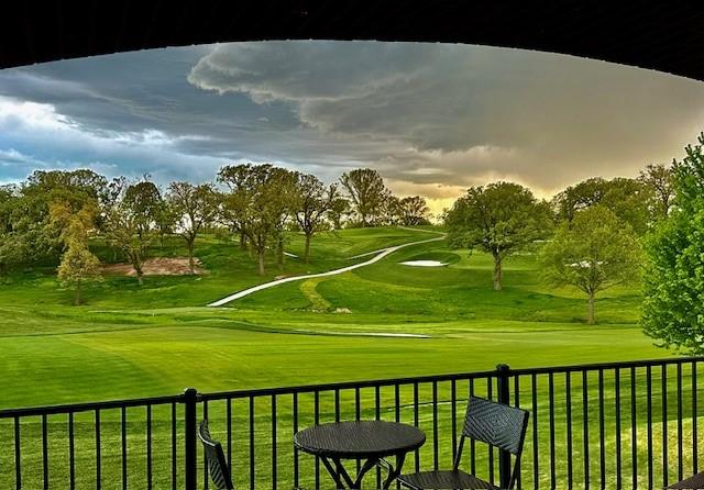 view of property's community with a yard, view of golf course, and fence