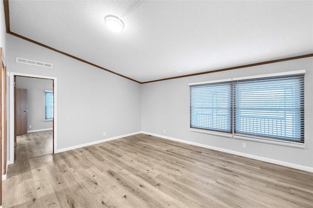 unfurnished room with light wood-type flooring, vaulted ceiling, plenty of natural light, and a textured ceiling