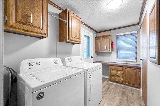 laundry room featuring a textured ceiling, washer and clothes dryer, cabinets, light hardwood / wood-style flooring, and crown molding