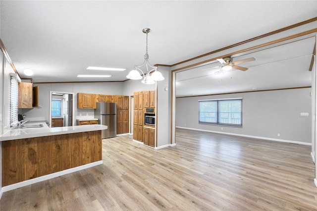 kitchen with sink, hanging light fixtures, kitchen peninsula, ornamental molding, and stainless steel refrigerator