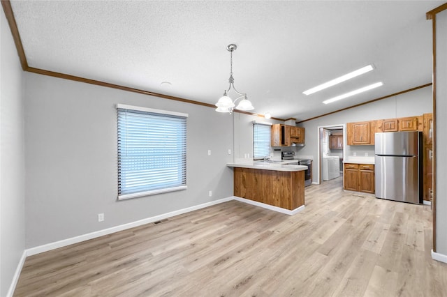 kitchen with kitchen peninsula, pendant lighting, vaulted ceiling, washer / dryer, and appliances with stainless steel finishes