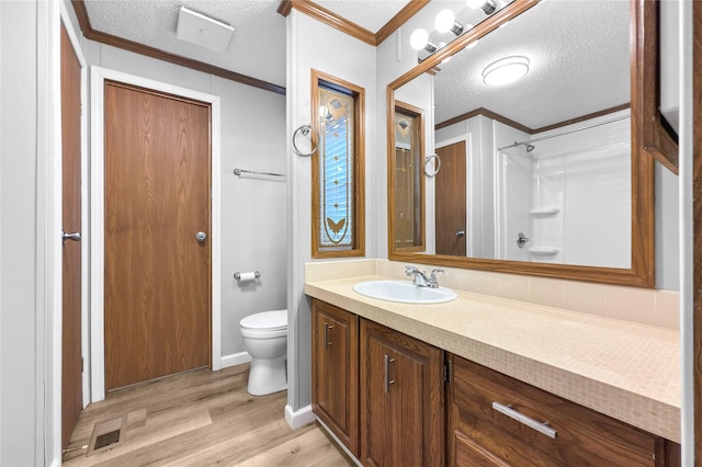 bathroom featuring a textured ceiling, toilet, crown molding, and hardwood / wood-style floors