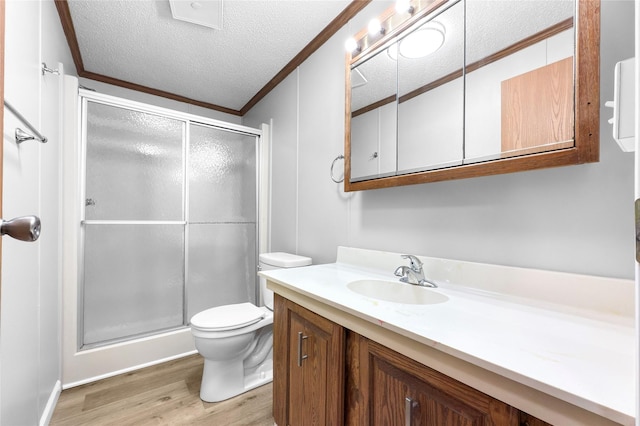 bathroom featuring a textured ceiling, hardwood / wood-style floors, vanity, walk in shower, and crown molding