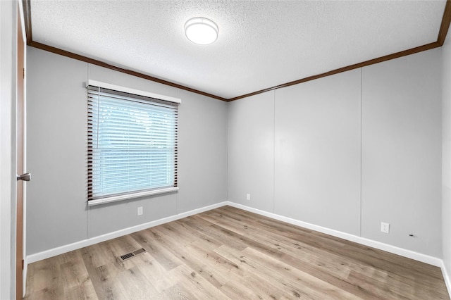 spare room with light hardwood / wood-style floors, a textured ceiling, and ornamental molding