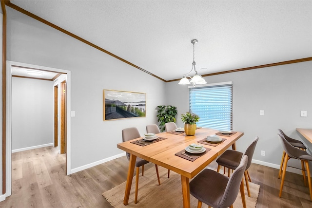 dining space with crown molding, light wood-type flooring, a chandelier, and vaulted ceiling