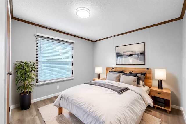 bedroom featuring ornamental molding, light hardwood / wood-style floors, and a textured ceiling